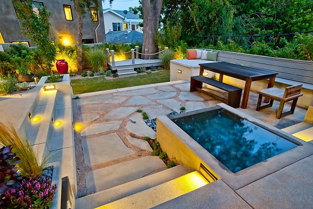 outdoor spa in a patio with stone benches and wooden table
